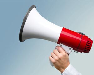 Hand holding red and white megaphone.